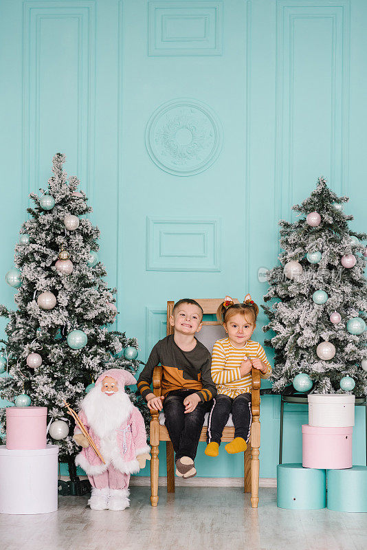 Childs playing near Christmas tree. Happy children hugging at a home. Brother and sister. Happy New Year and Merry Christmas. Ð¡oncept of a family holiday. Decorated interior room of a house. Closeup.